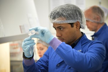 A man in hair net holding a conical centrifuge tube